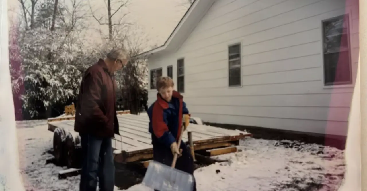A young Robbie Poe shoveling snow beside a utility trailer