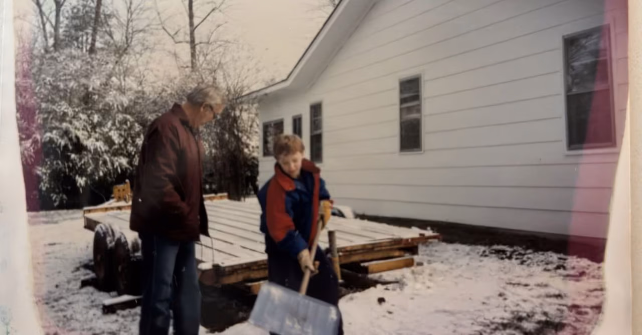 A young Robbie Poe shoveling snow beside a utility trailer